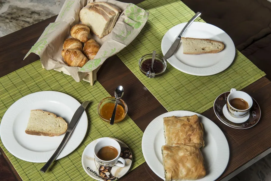 Πρωινό με ψωμί, πίτες και καφέ σε πράσινο τραπεζομάντιλο